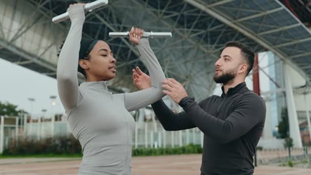 Odaklanmış Fitness Eğitmeni Dambıllı Genç Bayana Dışarıda Egzersiz Yaptırıyor Sağlık — Stok video