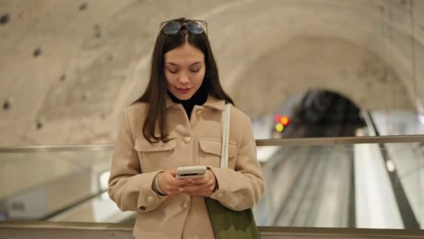 在地铁地铁站等候时 身穿休闲装的年轻女性专心致志地使用智能手机 — 图库视频影像