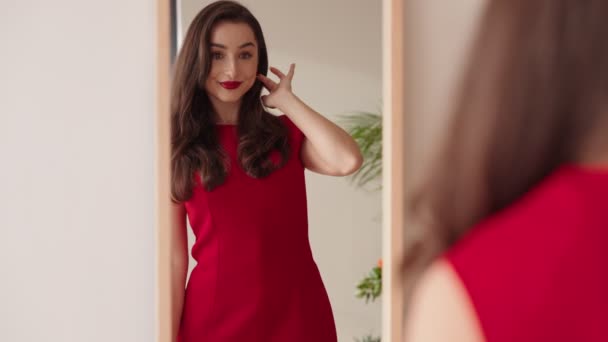 Γοητευτική Νεαρή Γυναίκα Ένα Ζωντανό Κόκκινο Φόρεμα Ελέγχει Την Εμφάνισή — Αρχείο Βίντεο