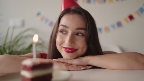 笑顔の若い女性は彼女の誕生日を祝い ライトキャンドルでケーキの横に願いを作り 喜びと祝賀を伝える — ストック動画