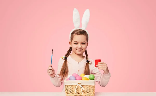 Zawartości Dziewczynka Siedzi Przy Stole Farby Kolorowanki Wielkanocne Jaja Różowym Zdjęcia Stockowe bez tantiem
