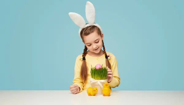 Glückliches Mädchen Mit Zöpfen Trägt Weiße Hasenohren Und Findet Ostereier lizenzfreie Stockbilder