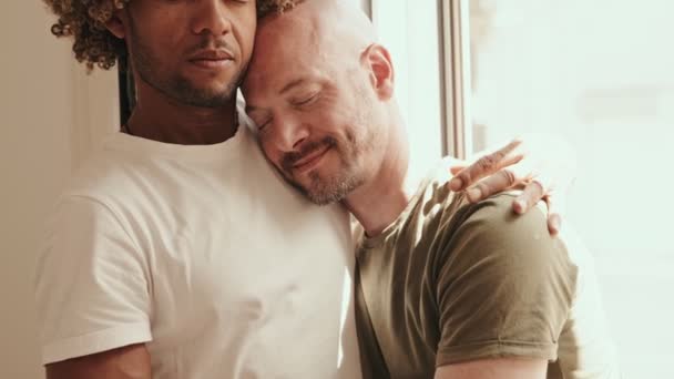 Cuplu Homosexual Interrasial Care Îmbrățișează Fereastră Împărtășind Îmbrățișare Liniștitoare Afectuoasă — Videoclip de stoc