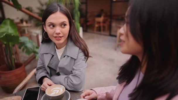 2人の若い女性がカフェでコーヒーを飲みながら 彼女の友人に意図的に耳を傾けながら一瞬を共有しています — ストック動画