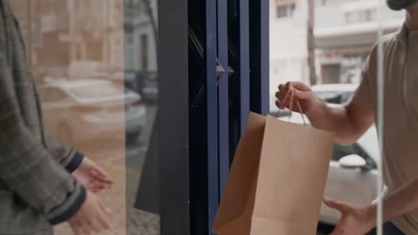 Närbild Händer Utbyta Papperspåse Genom Dörröppning Symboliserar Säker Kontaktlös Matleverans — Stockvideo