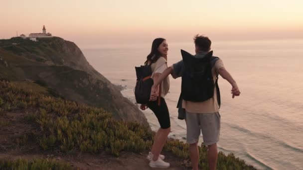 一位年轻男女的肖像 举手表决 日落时分 在海滨悬崖边的小径尽头欢庆 传达着成就和冒险 — 图库视频影像