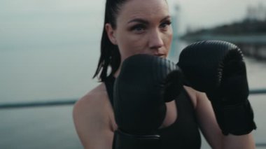 Eğitimden önce özgüven ve kararlılık saçan, boks eldivenli odaklanmış bir kadının yakın çekimi..