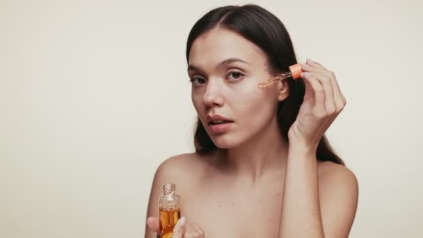 一位安详的年轻女性小心地涂上了滴在脸上的化妆品油 促进了自我护理和皮肤护理的日常活动 理想的美与健康概念 — 图库视频影像