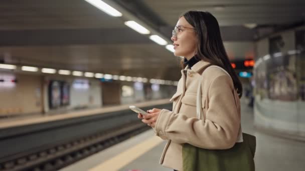 Young Woman Eyeglasses Engaging Her Phone Patiently Waiting Train Clean — Stock Video