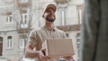 Dost canlısı kurye, şehir arka planındaki bir müşteriye bir paket veriyor, etkin hizmet sunuyor.