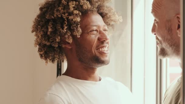 Щаслива Різноманітна Гей Пара Ділиться Мить Посміхаючись Розмовляючи Біля Вікна — стокове відео