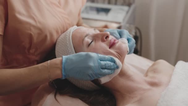 Cosmetologist Luvas Azuis Limpa Suavemente Rosto Mulheres Relaxadas Preparando Pele — Vídeo de Stock