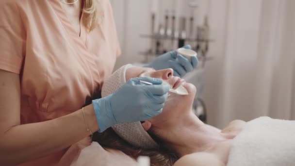 一位熟练的美容师用刷子轻柔地涂在病人脸上的治疗面罩上 让病人在温泉里放松一下 — 图库视频影像
