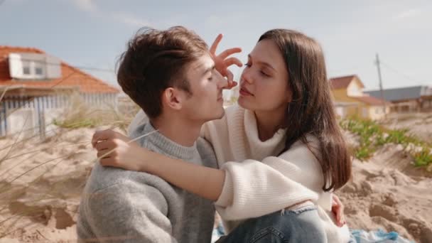 一对有爱心的年轻夫妇温柔地拥抱在一起 在沙滩沙丘上享受着宁静的时光 背景是柔和的重点住宅 象征着浪漫和爱情 — 图库视频影像