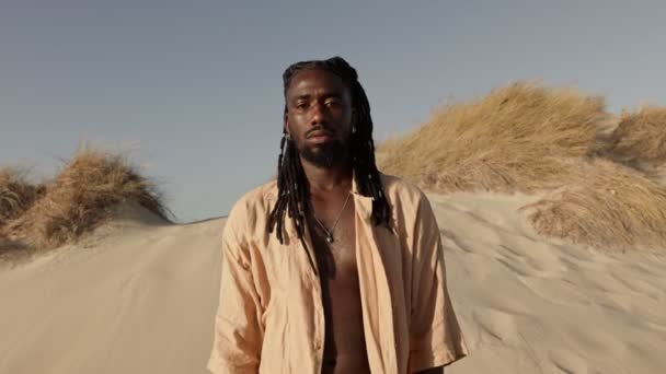Kontemplativní Africký Muž Dredy Volnou Košilí Stojící Písečné Pláži Během — Stock video