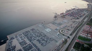 Hava kararırken kargo, konteynır ve araçlarla dolu sanayi limanının genişleyen altyapısını görüntülüyoruz..