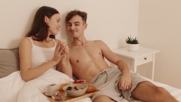 愛するカップルは ベッドで居心地の良い朝食を食べながら柔らかい瞬間を共有し 暖かさと愛情を受け入れる — ストック動画