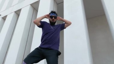Sokak dansçısı bir erkek hip-hop dansçısı dansını açık havada modern bir şehir planıyla sergiliyor..