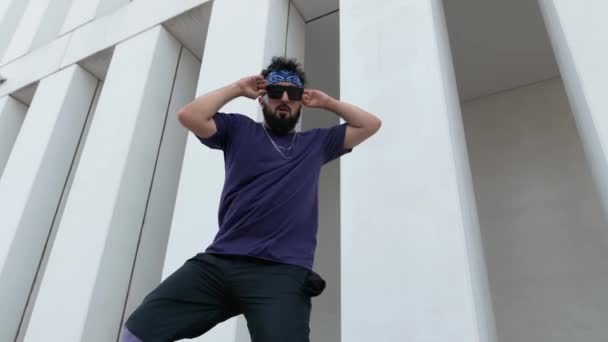 街头的一名男子嘻哈舞蹈演员穿着以现代城市建筑为背景的服装 展示自己的舞步 — 图库视频影像