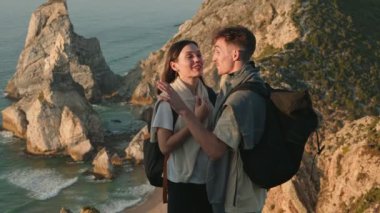 Mutlu çift, sahil boyunca uzun bir yürüyüşten sonra gün batımının tadını çıkarır. Birlikte güzel bir anı paylaşır, ufku işaret eder..