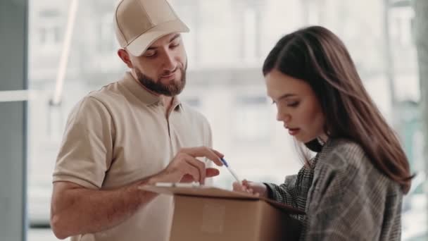 一个送货员在一个年轻的女客户为收到的包裹签名时等待 描述了一个日常的物流场景 赢得了信任和服务 — 图库视频影像