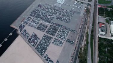 Deniz kenarında uluslararası ihracat için düzenlenmiş sıra sıra arabalarla geniş bir liman altyapısını gösteren bir hava görüntüsü..
