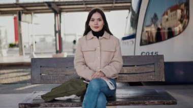 Çağdaş bir tramvay istasyonunda toplu taşıma bekleyen genç bir kadın, kentsel seyahat ve sükuneti somutlaştırıyor..