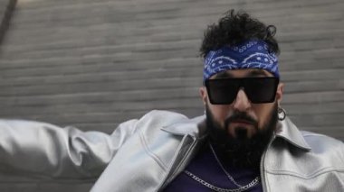 Sakallı kendine güvenen hip hop dansçısı açık havada dans ediyor. Gümüş ceket ve sokak tarzı moda, şehir dans kültürünü ifade ediyor..