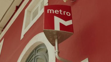 Canlı kırmızı bir metro tabelasının şehir merkezinde canlı kırmızı bir bina duvarına yakın plan..