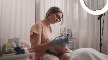 Klinikteki bir güzellik terapisti müşteriye iyontoforez yüz tedavisi uyguluyor. Sağlık ve cilt bakımı.
