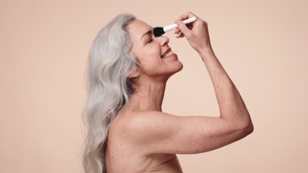 Radosna Seniorka Siwymi Włosami Używająca Jadeitowego Wałka Twarzy Beżowym Tle — Wideo stockowe