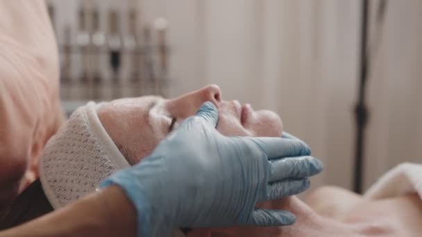 Skicklig Kosmetolog Applicerar Varsamt Ansiktsmask Avslappnad Kvinnlig Klient Lugn Spa — Stockvideo