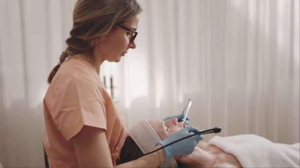 Виділений Косметолог Салоні Забезпечує Спокійне Лікування Обличчя Клієнту Демонструє Скінарій — стокове відео