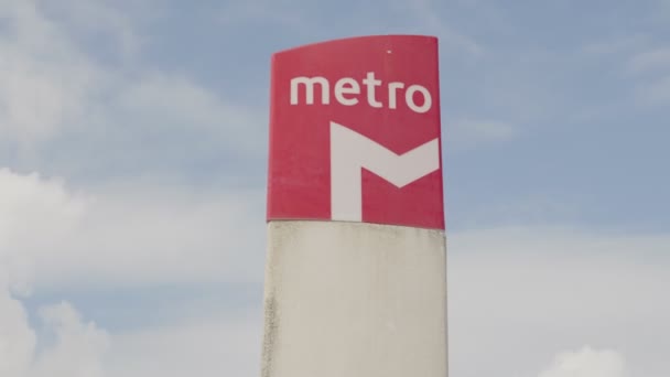 バックグラウンドに青空が澄んだポールに 活気あふれる赤い地下鉄駅のサインが 都市通勤を象徴しています — ストック動画