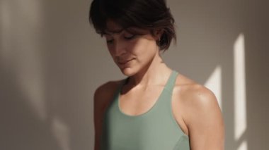 Stüdyo ortamının yumuşak, doğal güneş ışığıyla yıkanmış sağlıklı ve sağlıklı bir esmer kadının yakın çekimi..