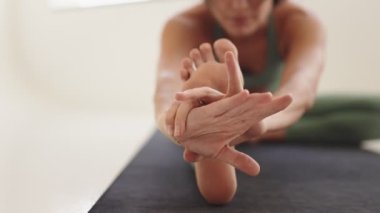 Bir yoga ortamında hassas ve sakin bir görünüm sergileyen, oturarak asana dansı yapan insanların el ve ayaklarına odaklanmış..