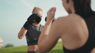 Dışarıda boks antrenmanı yapan iki atletik kadın azim ve güç gösteriyorlar..