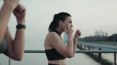 İki aktif kadın kişisel antrenörle açık hava boks antrenmanında sahne arkası manzarasına karşı..