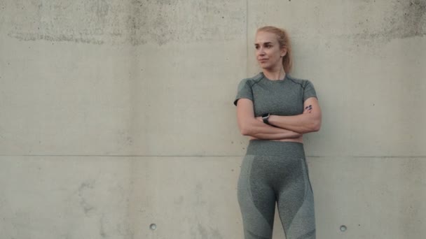 スポーティブな女性は 彼女のトレーニング服のコンクリートの壁に自信を持ってプッシュし 夕暮れ時に強さと決意を示しています — ストック動画