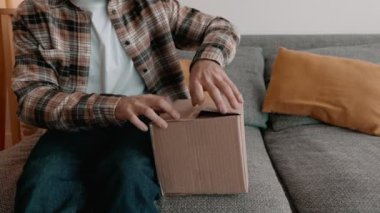 Samimi bir an, evinde bir adamı koltuğunda rahat bir şekilde otururken heyecan içinde bir karton kutuyu açarken yakalar. Ayarlar rahat ve rahat bir atmosfer olduğunu gösteriyor..