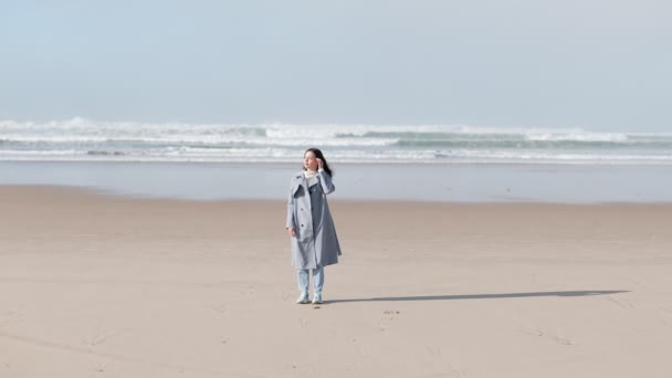 Una Mujer Reflexiva Una Gabardina Disfruta Soledad Una Playa Expansiva — Vídeos de Stock