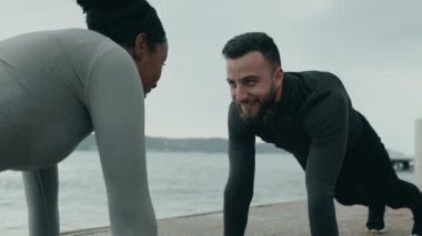 Atletizm dalındaki iki kişi liman kenarındaki antrenmana hazırlanırken motivasyon ve aktif yaşam tarzına odaklanmış, çekirdek kaslarını çalıştırıyor..