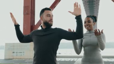 İki fitness arkadaşı birlikte eğlenceli bir antrenman seansına katılıyor, bir şehir zeminine karşı, gülümsüyor ve aktif kalıyorlar..