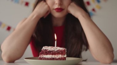 Tanınmayan bir kadın doğum günü pastasıyla tek başına oturmuş, tecritteki özel gününü kutlarken yalnızlık hissi uyandırıyor..