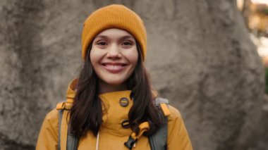 Sıcak sarı elbiseli ve sırt çantalı aktif genç bir kadın yürüyüş macerasının tadını çıkarıyor, dışarıda mutluluk ve macera yayıyor..