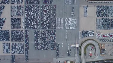 Geniş bir liman otoparkında düzgünce park edilmiş, uluslararası deniz kargo ihracatı için bir gemiye yüklenmeye hazır birçok arabanın yukarıdan aşağı görüntüsü..