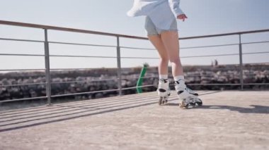Güneşli bir terasta paten kayan genç bir kadın boş zamanlarının tadını çıkarıyor. Sahne, özgürlük ve eğlence hissini tasvir ediyor..
