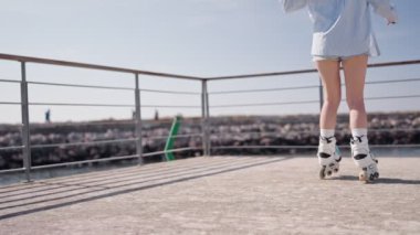 Deniz kenarında güneşli bir günde paten kayan bir kadın. Açık hava aktivitelerinin ve özgürlüğün tadını çıkarıyorum. Etkin yaşam biçimi.