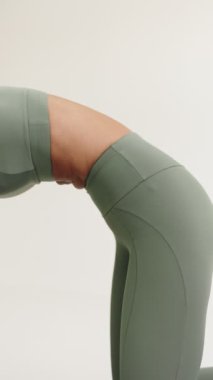 Kadın bir yoga uygulayıcısının vücut esnekliğini ve formunu sakin bir ortamda sergilediği yakın plan görüntüsü..