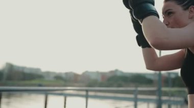 Kendini adamış boksör bir kadın, altın saat boyunca boks takımlarına sert yumruklar atıyor..